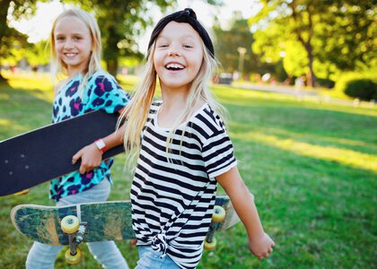 To jenter som ser glade ut, med skatebord under armen - Klikk for stort bilde